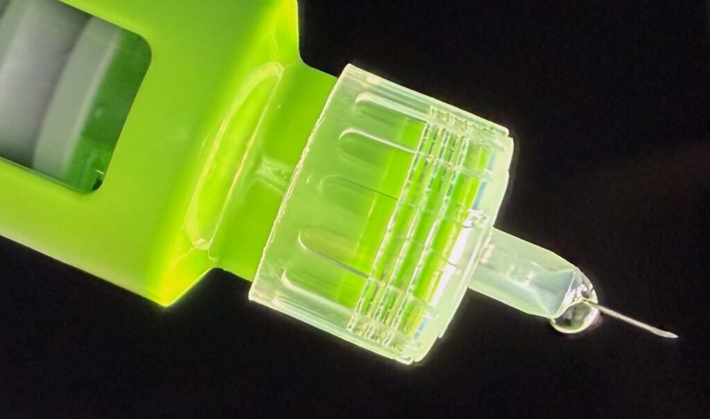 marco legal: close-up de uma caneta de aplicação de medicamento verde-limão com uma agulha e uma pequena gota de líquido na ponta.