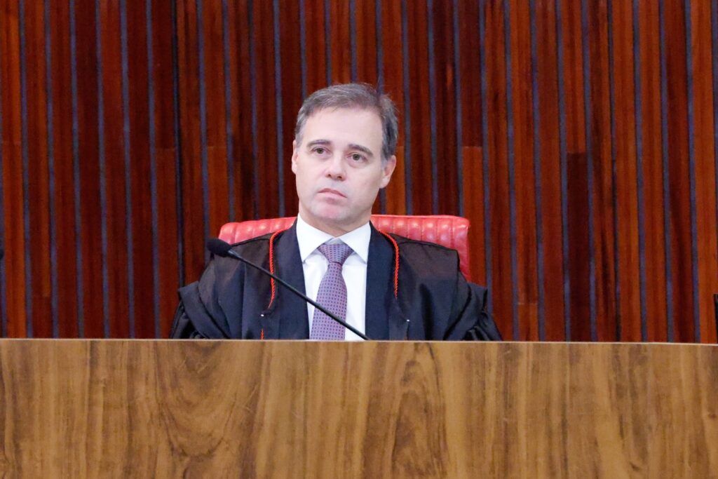 O ministro André Mendonça veste toga durante sessão plenária em tribunal.