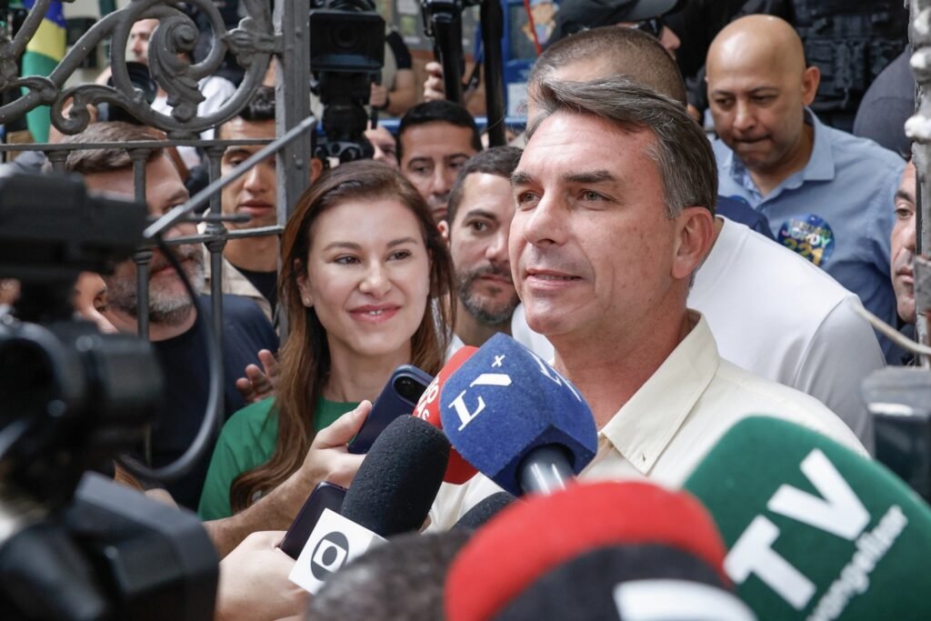 agenda dos candidatos: Flávio Bolsonaro fala ao microfone cercado por jornalistas e populares.