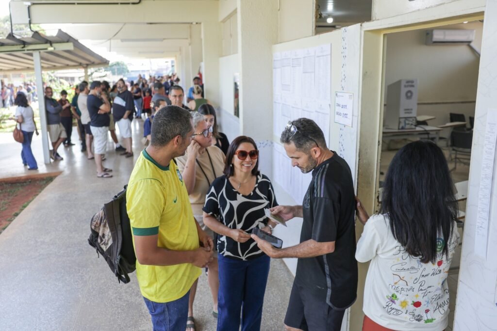 Eleitores consultam listas e aguardam em locais de votação durante o pleito.