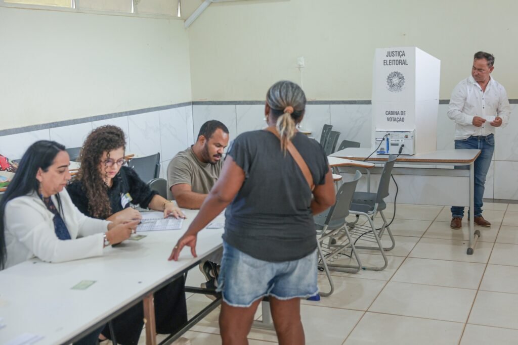 eleições 2026: eleitores e mesários em seção de votação com urna eletrônica.