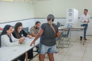 eleições 2026: eleitores e mesários em seção de votação com urna eletrônica.
