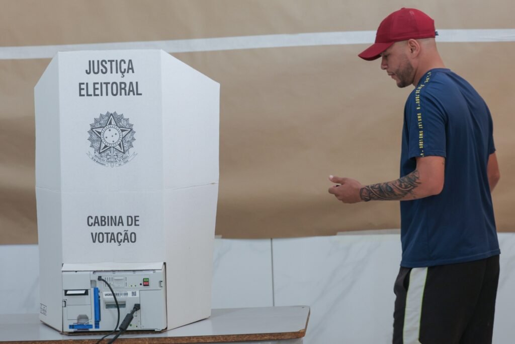 boca de urna: eleitor com boné vermelho vota em urna eletrônica da Justiça Eleitoral.