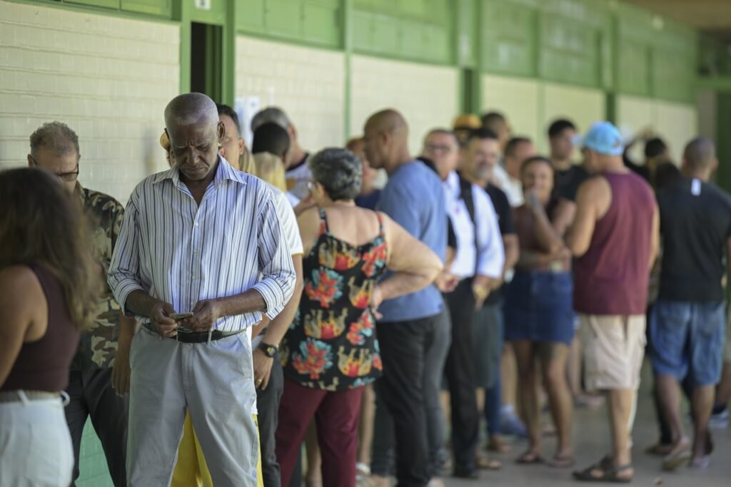 documentos para votar: Eleitores aguardam em fila para votação em seção eleitoral no Brasil.