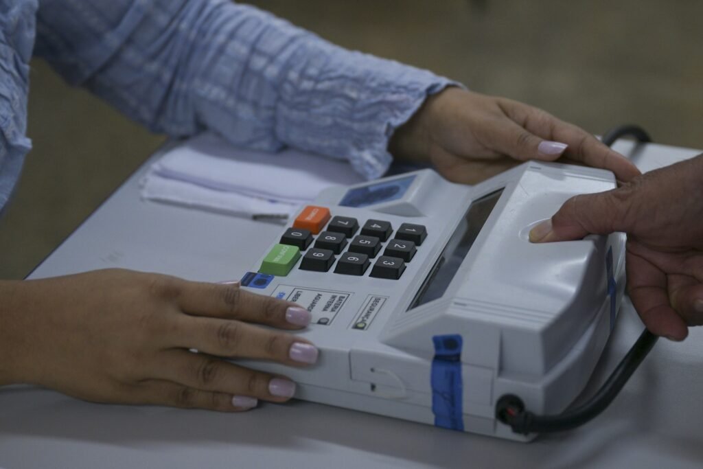 Mãos operam o teclado de uma urna eletrônica em votação para o segundo turno das eleições.