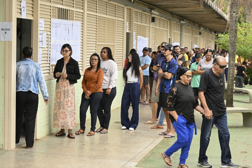 eleitores com 70 anos ou mais: pessoas aguardam em fila ao longo de um corredor externo em dia de votação.