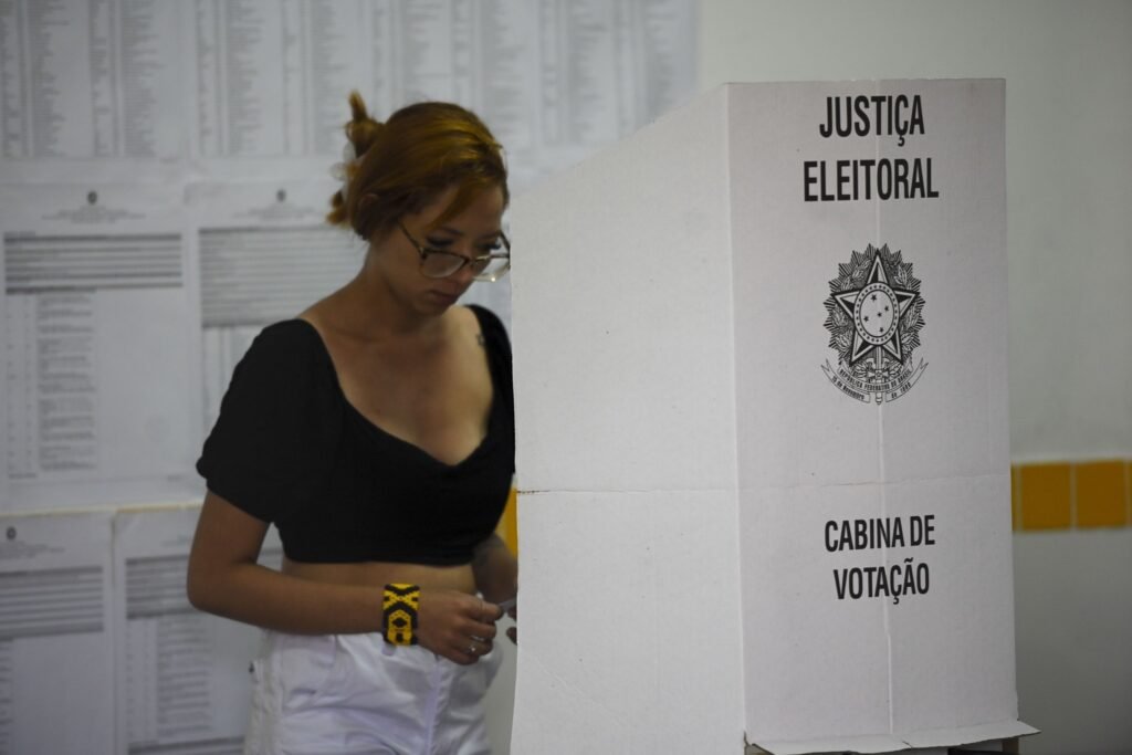 preferência política: eleitora vota em cabine de papelão com os dizeres Justiça Eleitoral.