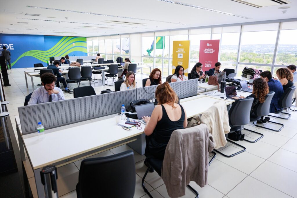 TSE: sala de imprensa com jornalistas trabalhando em estações de trabalho durante cobertura de eleições.