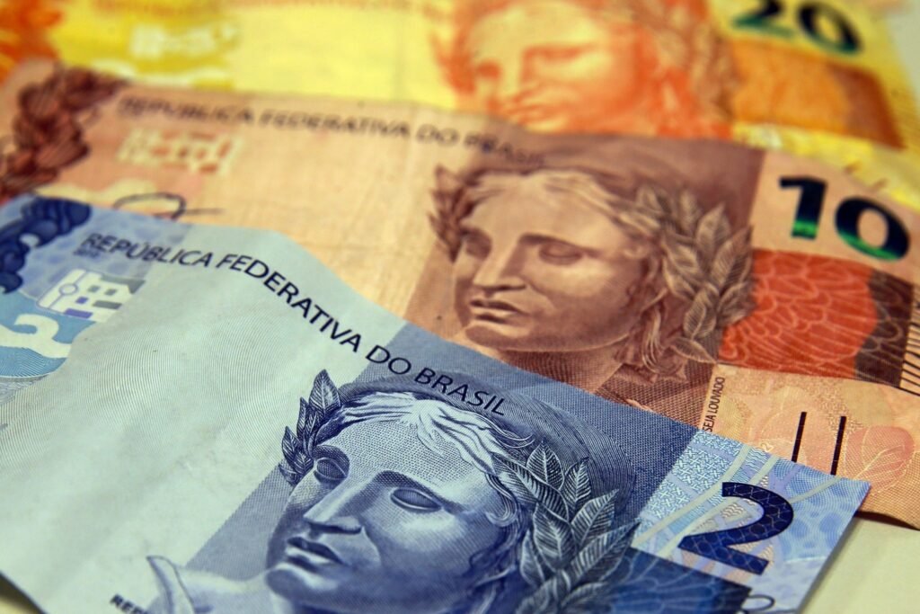 willer tomaz: Cédulas de Real brasileiro sobrepostas em close, destacando notas de menor valor e dizeres oficiais.