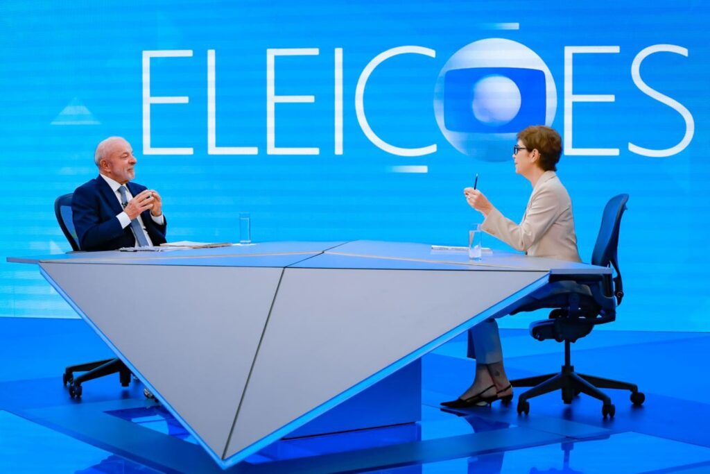 maioridade penal: Luiz Inácio Lula da Silva participa de entrevista sentado à mesa em estúdio de televisão com o painel 'ELEICOES' ao fundo.