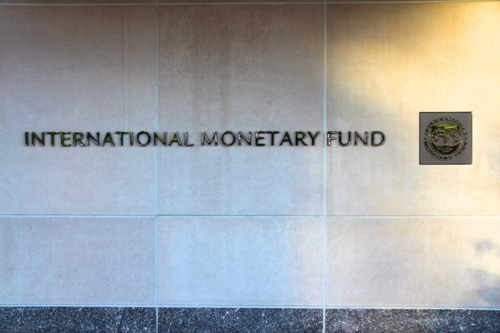 Fachada do Fundo Monetário Internacional com o letreiro "INTERNATIONAL MONETARY FUND" fixado em parede de pedra clara.