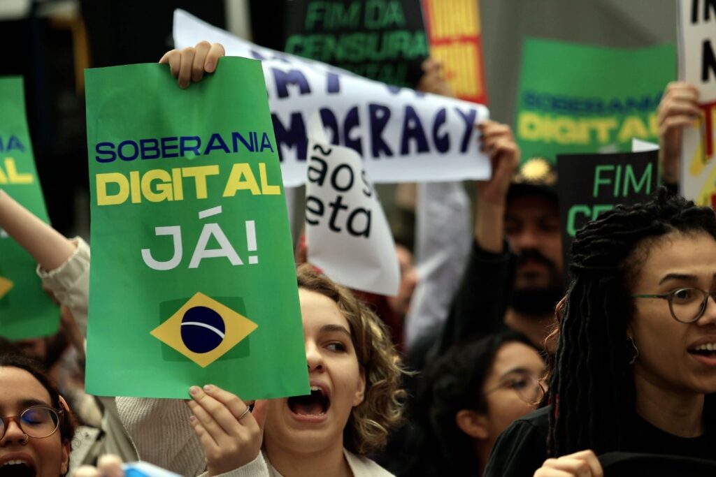 eleicao brasileira: Manifestantes gritam durante protesto, segurando cartaz com os dizeres 'SOBERANIA DIGITAL JÁ!'