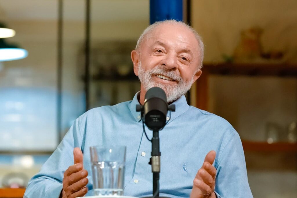 voto dos idosos: O presidente Luiz Inácio Lula da Silva sorri durante transmissão, gesticulando próximo a um microfone.