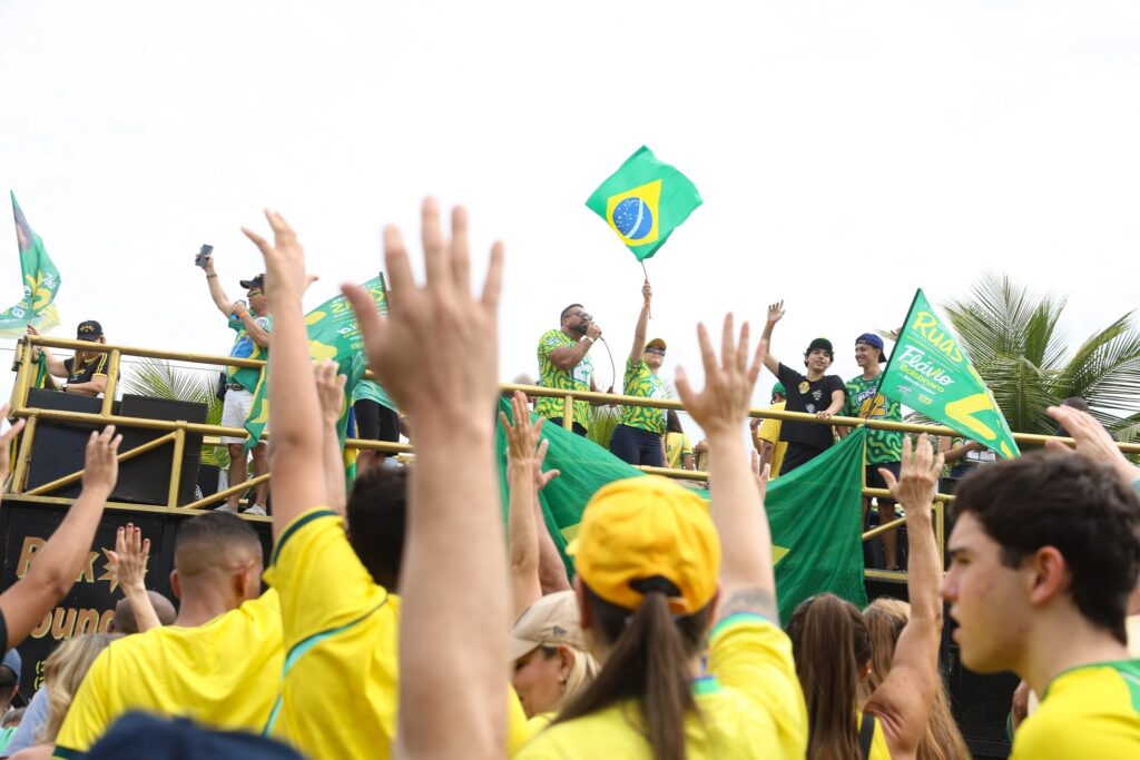 crime racista: Apoiadores em ato político vestindo camisas amarelas e segurando bandeiras e faixas de campanha.