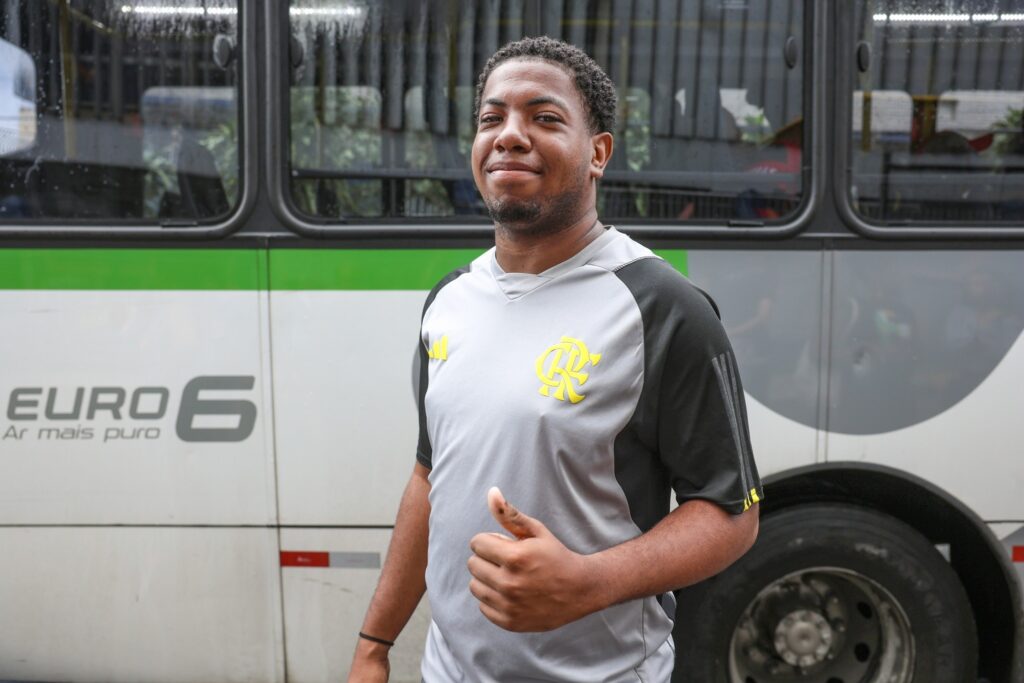 transporte público em Salvador: eleitor sorri e faz sinal positivo em frente a um ônibus urbano.