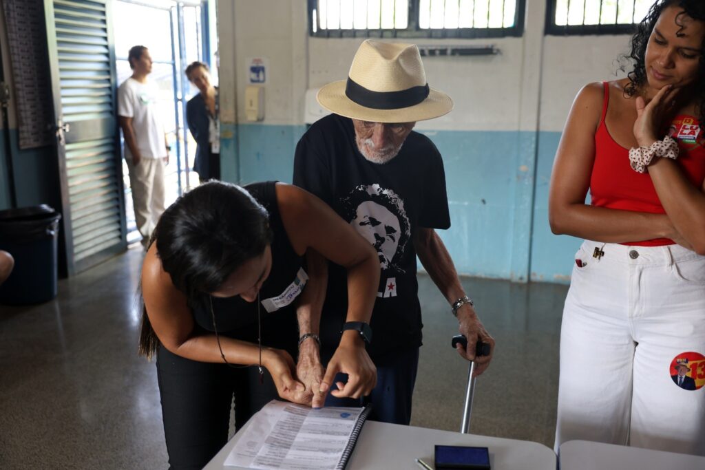 votacao em Salvador: eleitor idoso é auxiliado por mesária a registrar a digital em leitor biométrico de urna eletrônica.