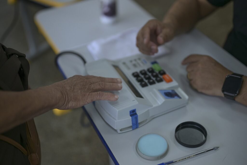 Mailza Assis: eleitora posiciona a mão sobre o leitor biométrico de uma urna eletrônica durante votação.