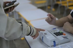 Donald Trump: eleitor aponta o dedo para urna eletrônica em seção eleitoral durante as eleições no Brasil.