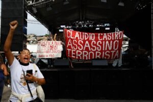 operacao contencao: Mulher grita com o punho erguido em ato no Complexo da Penha, no Rio de Janeiro.