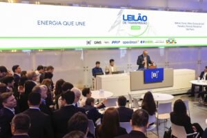alta do dólar: Auditório da B3 durante leilão de transmissão de energia, com homem discursando na tribuna.